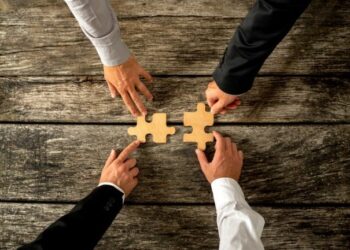 four hands with two puzzle pieces