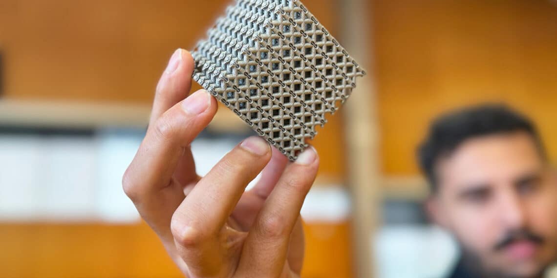 PhD candidate Jordan Noronha holding a sample of the new titanium lattice structure 3D printed in cube form. Credit: RMIT.